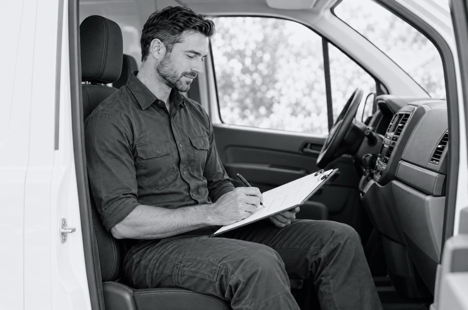 A technician in his van's front seat marking up a printed plan.