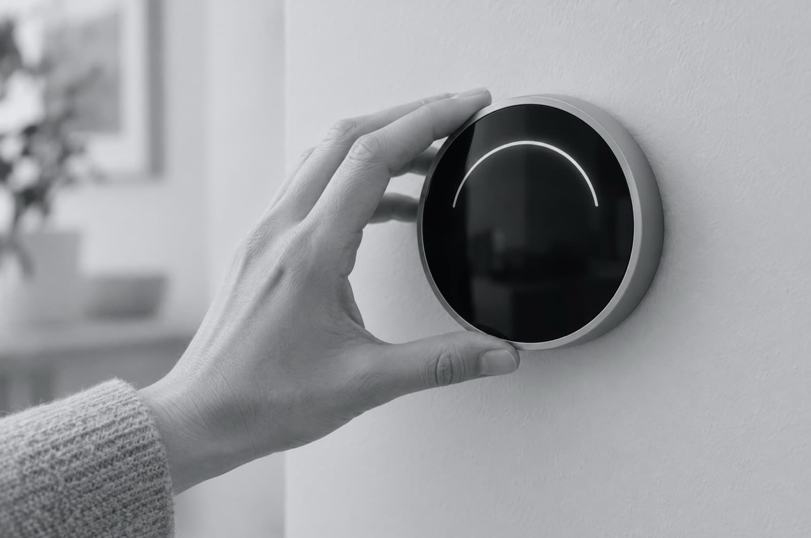 A hand turning a smart thermostat.
