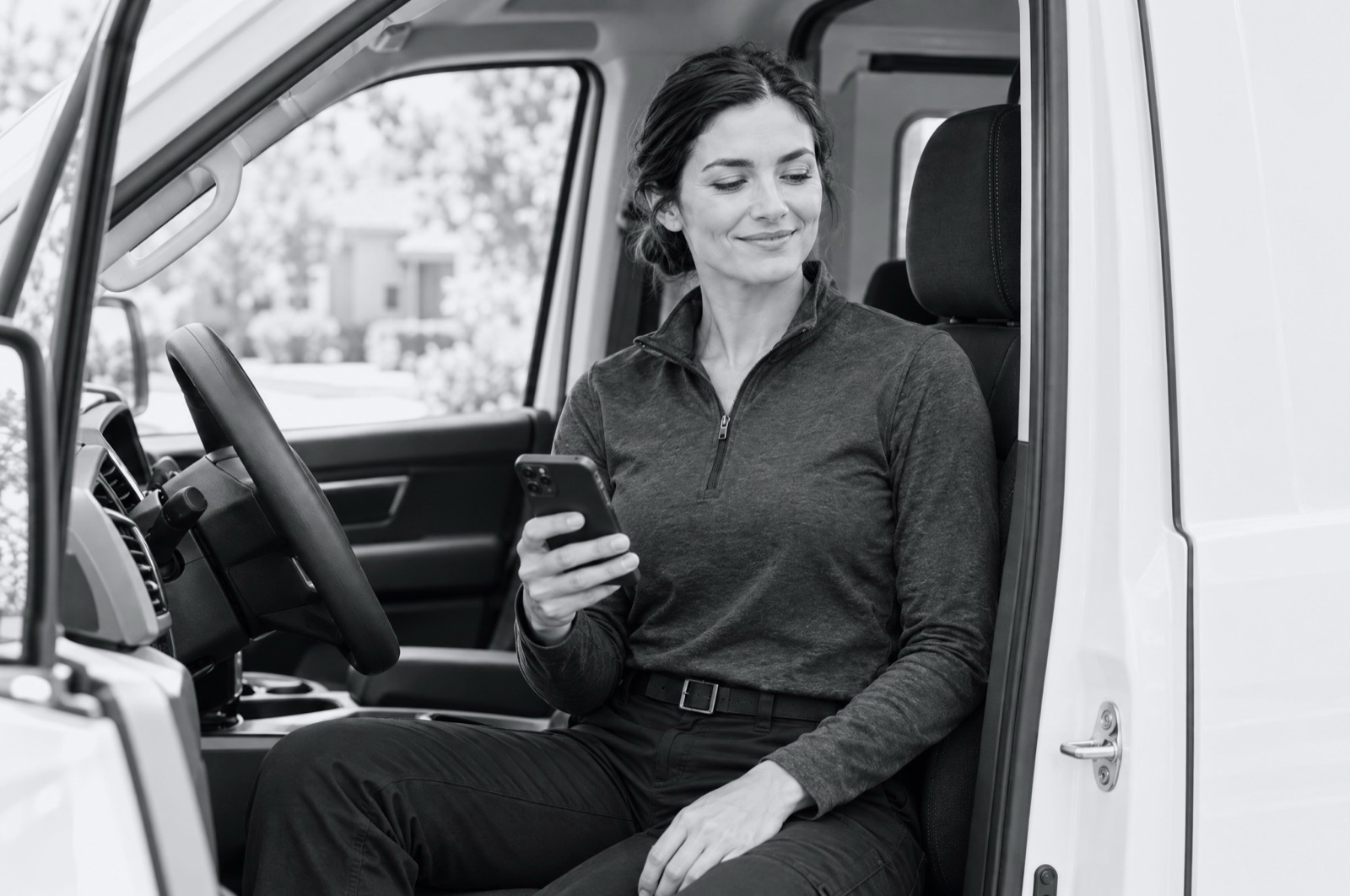 A technician in her van checking her phone between jobs.